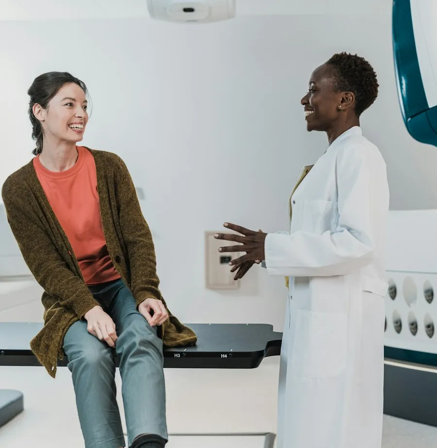 A smiling patient chatting with a clinician before her scan